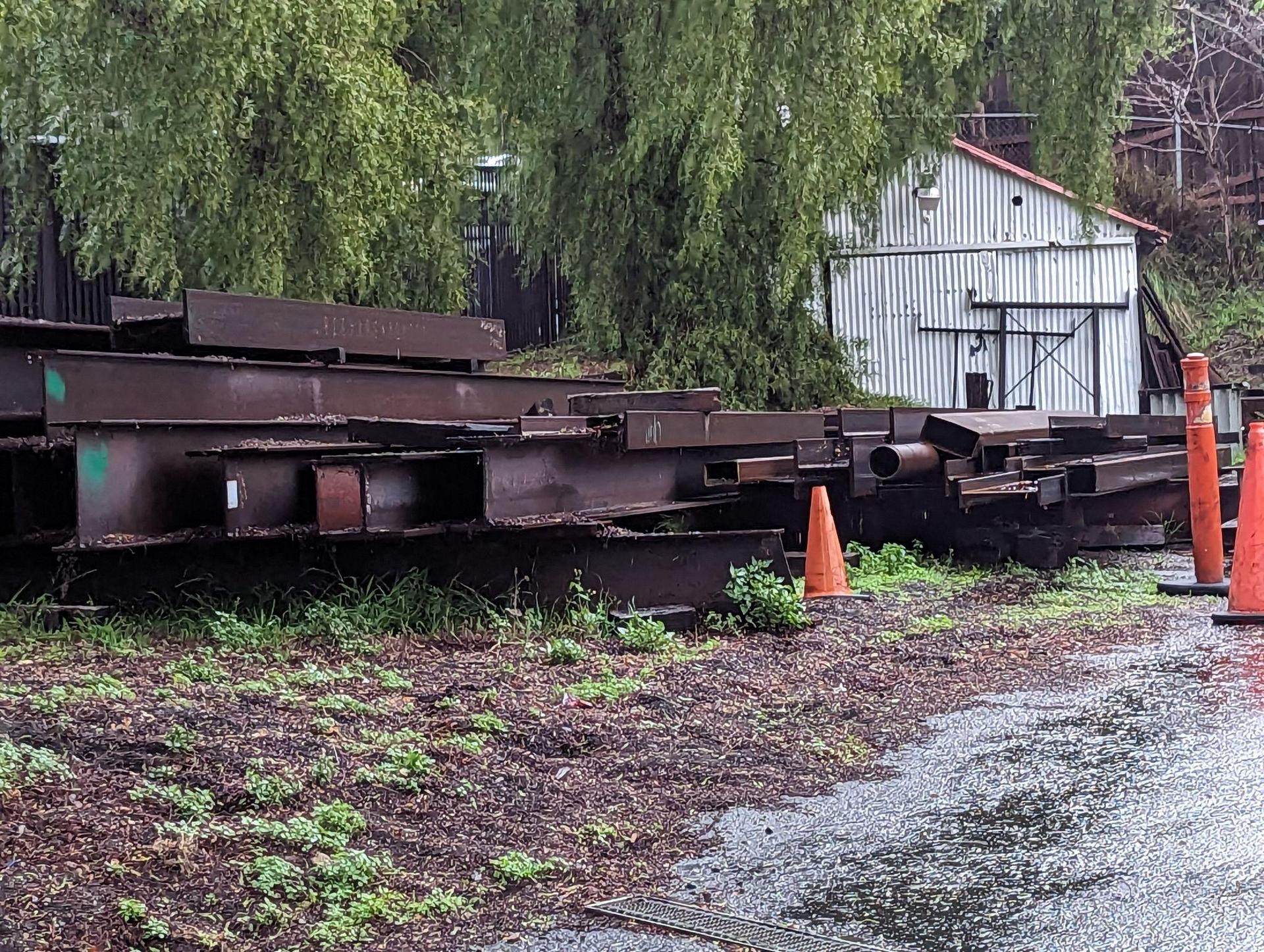 Rusty beams stored outside in the rain, uncovered at an industrial metal facility