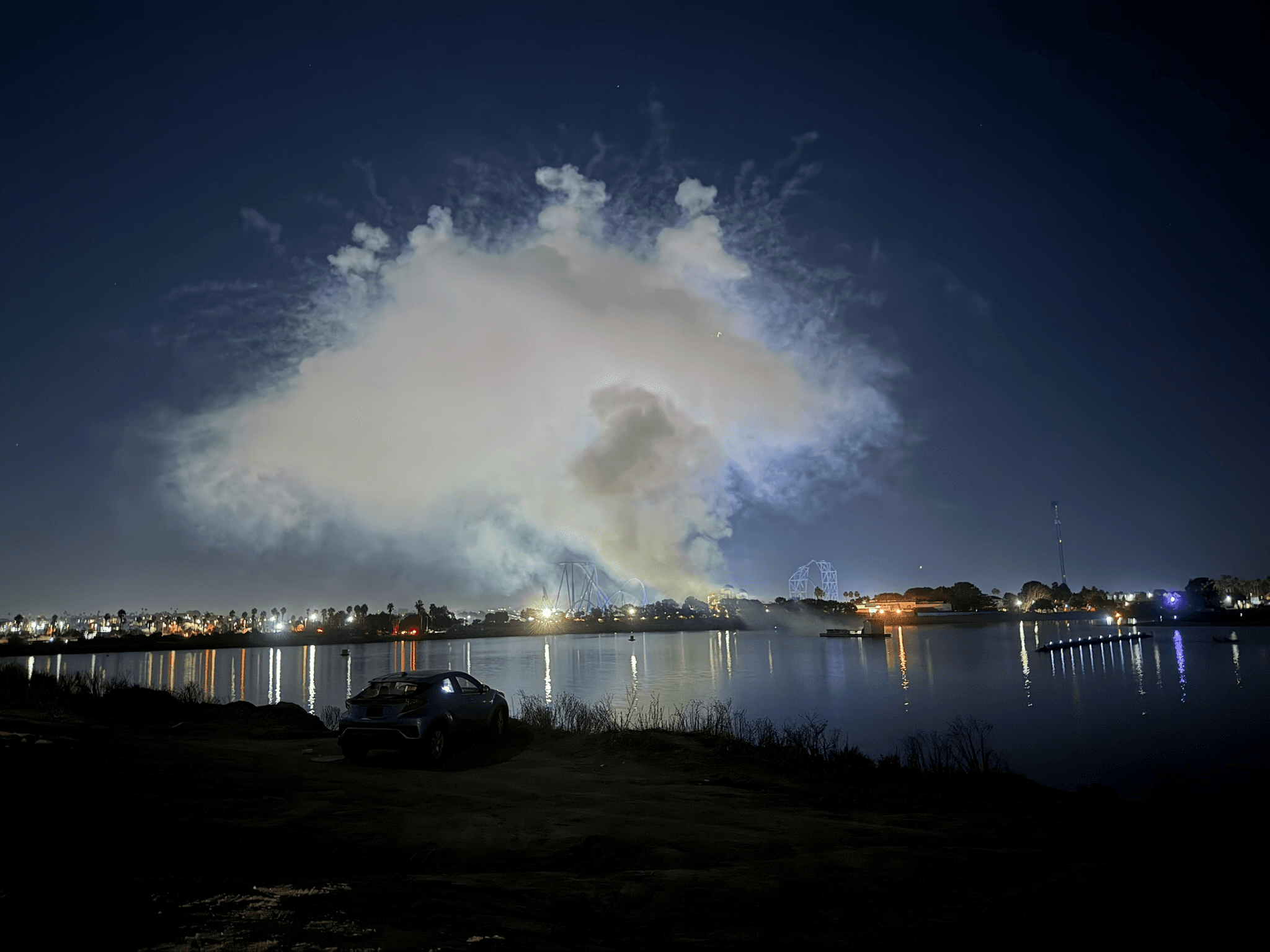 Smoke from a fireworks show drifting over Mission Bay at night near the SeaWorld barge
